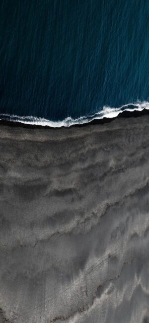 Aerial beach view with dark sands & blue ocean waves, contrasting a mesmerizing natural scene | 4K Wallpaper for Mobile