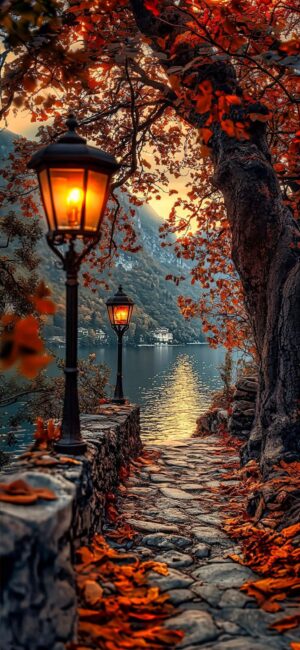 Stone path with vintage lamps, vibrant autumn leaves by a lake, and mountains in the distance | 4K Wallpaper, for Mobile