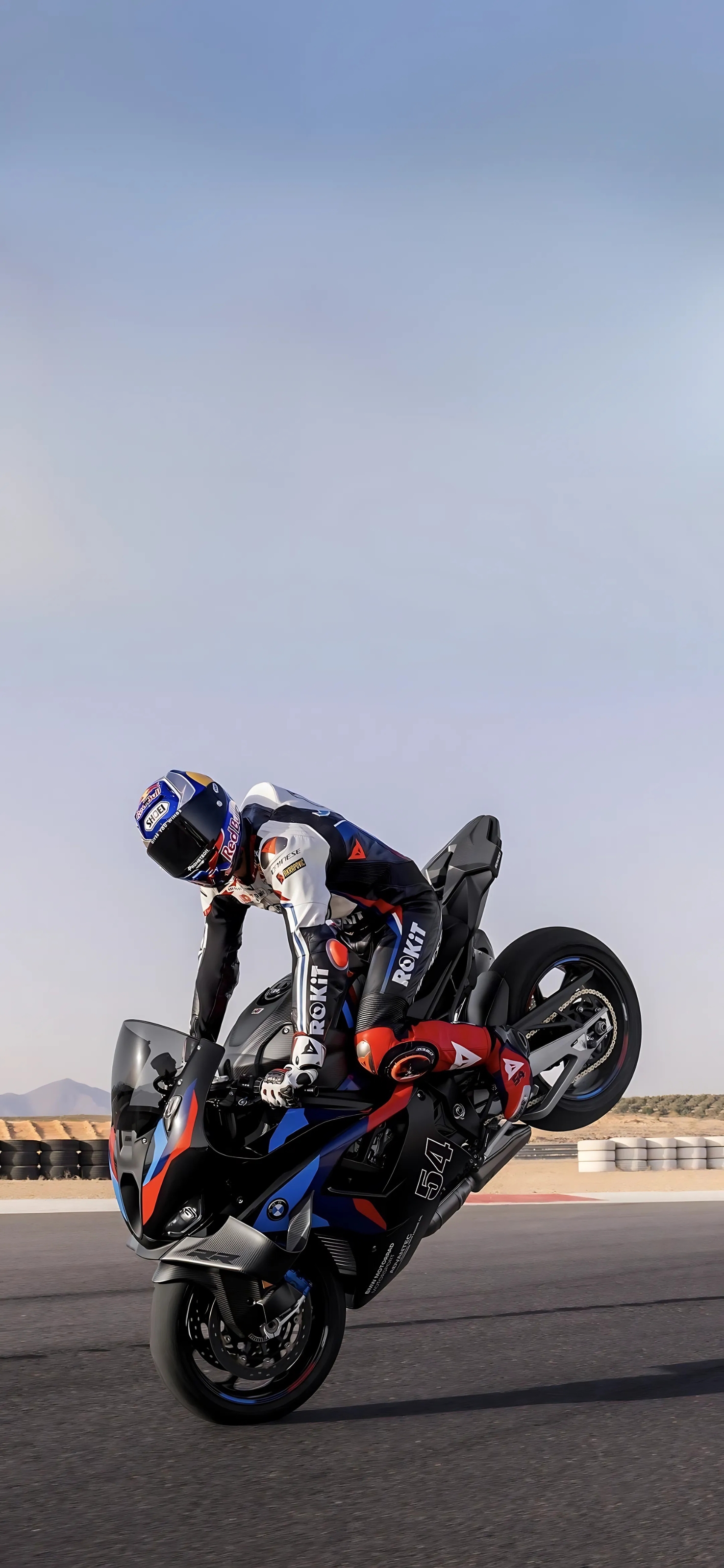 Motorcyclist doing a wheelie on a BMW sports bike on a race track under a clear sky | 4K Wallpaper for Mobile