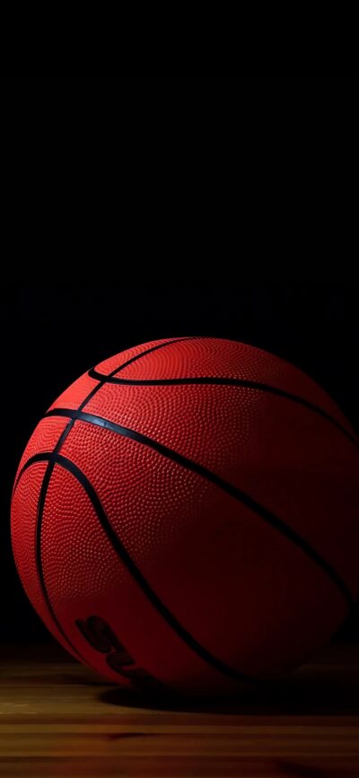 Basketball close-up on wooden court with intense texture and dark backdrop. Primary Colors: Orange, Black, Brown | 4K Wallpaper for Mobile