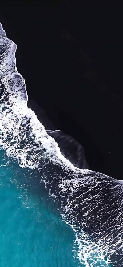 Aerial view of ocean waves on dark sandy shore, turquoise water contrasts with black sand | 4K Wallpaper for Mobile