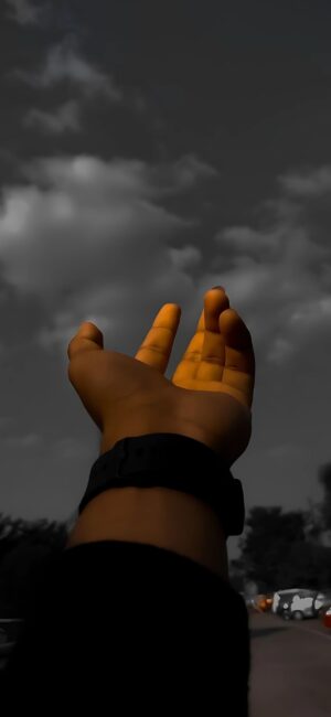 Outstretched hand in warm tones reaches a cloudy sky, exuding aspiration | 4K Wallpaper for Mobile | Black, Gray, Orange.