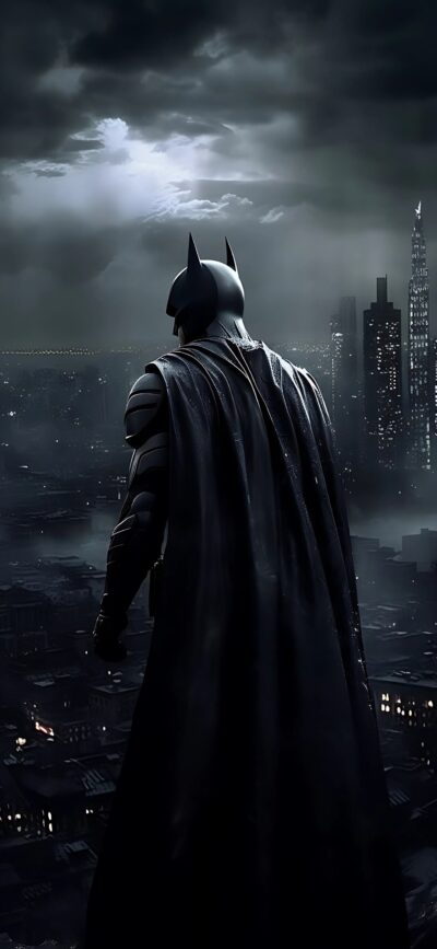 Batman stands on a rooftop, overlooking a dark, rainy cityscape | 4K Wallpaper for Mobile | Black & Gray | Batman, Superhero, Cityscape.