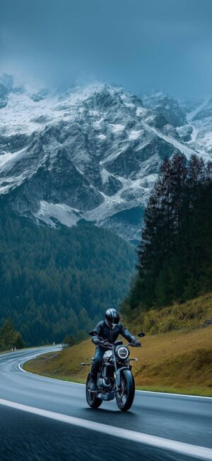 Motorcyclist on scenic mountain road with snow-capped peaks and lush hills | Adventure & Freedom | 8K Wallpaper for Mobile