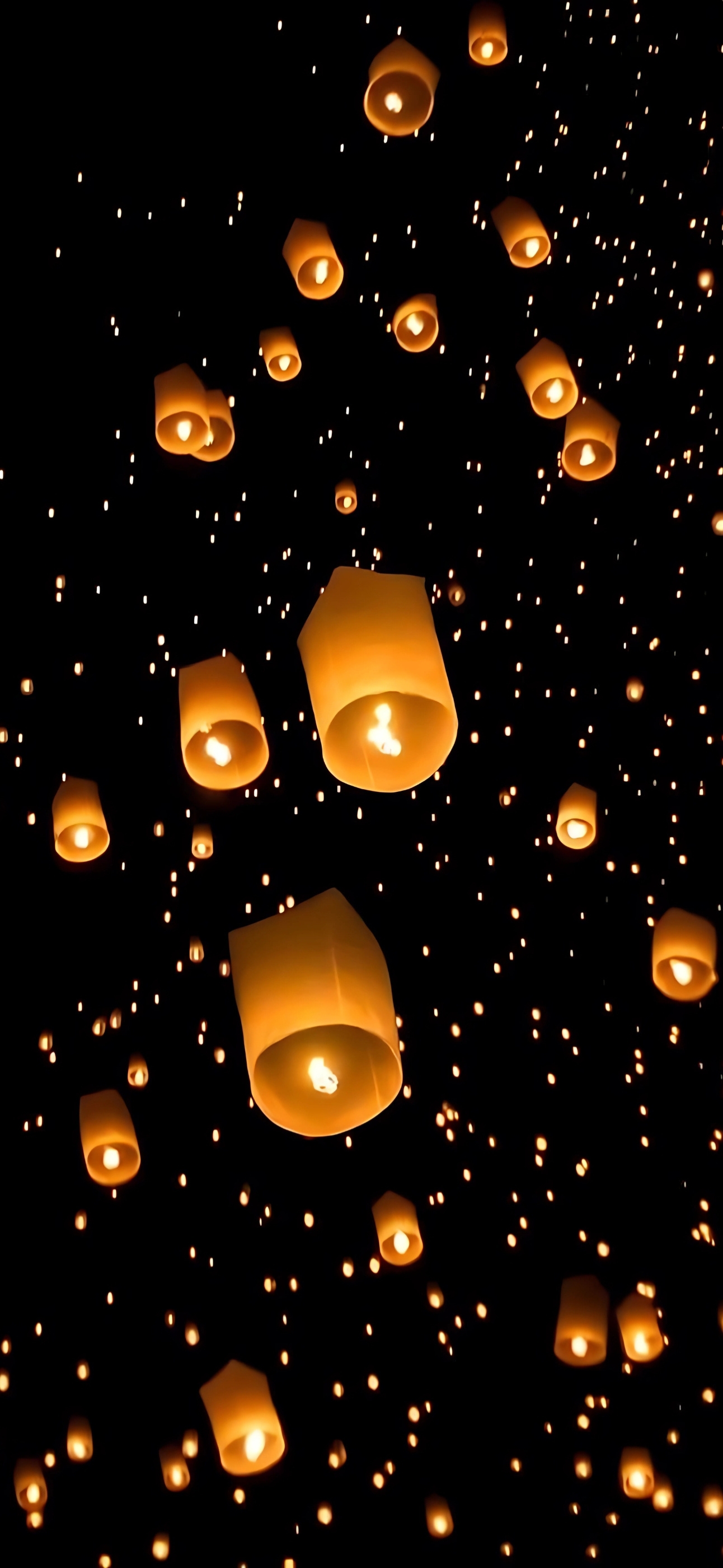 Floating lanterns illuminate a dark night sky, creating a serene ambiance. | Black, Orange | 4K Wallpaper for Mobile