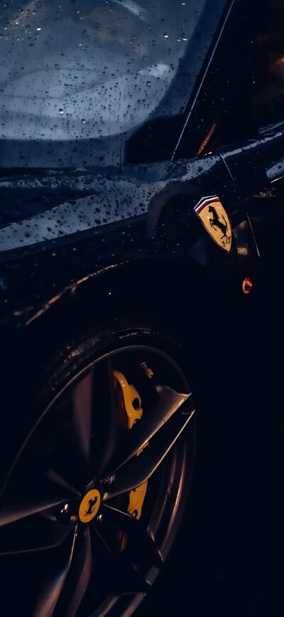 Ferrari car with iconic logo and wheel, raindrops enhance drama, featuring dark, black, yellow hues | 4K Wallpaper, for Mobile