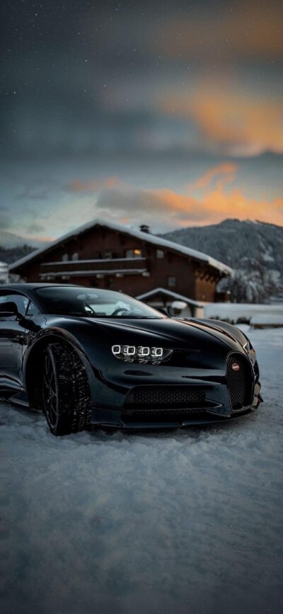 Sleek black luxury car against a snowy backdrop with cabin, mountains, and colorful sky | 4K Wallpaper for Mobile