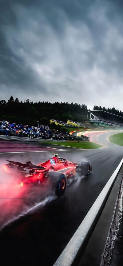 Red Formula 1 race car on a wet track with dark sky, water spray, and spectators | 8K Wallpaper for Mobile