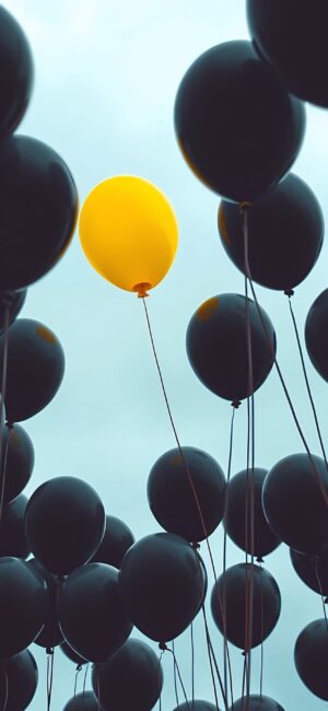 Yellow balloon amidst black ones against a sky backdrop symbolizes individuality | For Mobile | 4K Wallpaper | Yellow, Black, Blue colors