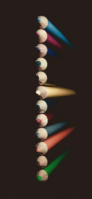 A vertical arrangement of colored pencils on dark background, featuring blue, pink, yellow, red, green | 4K Wallpaper for Mobile