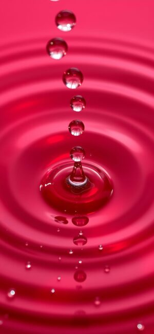 Pink liquid rippling with water droplets, abstract light and shadow interplay | 4K Wallpaper for Mobile