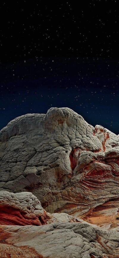 'Rugged rock formations under a starry night sky | 4K Wallpaper for Mobile | Gray, Black, Red hues | Perfect for nature & space lovers.'