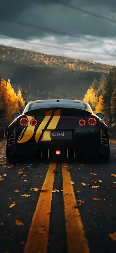 Black sports car with yellow stripes on a fall road, vibrant foliage, cloudy sky, mountains | 4K Wallpaper for Mobile