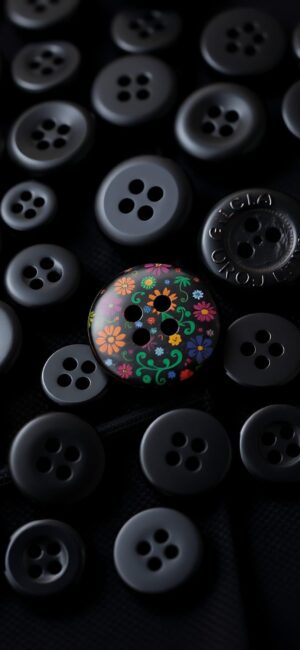 Black buttons with one colorful floral button, creating contrast. Primary: Black, Multicolor | 4K Wallpaper for Mobile