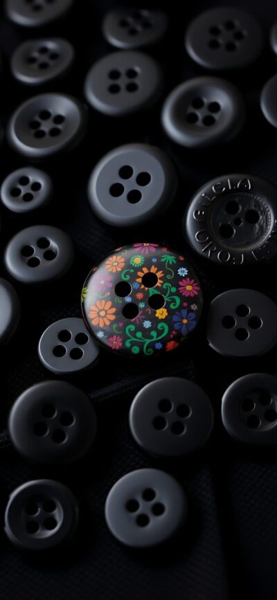 Black buttons with one colorful floral button, creating contrast. Primary: Black, Multicolor | 4K Wallpaper for Mobile