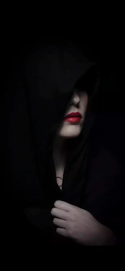 Hooded figure with red lips, black background creating a gothic tone | for Mobile | 4K Wallpaper.