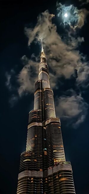 Burj Khalifa under a full moon with dramatic clouds, stunning city lights | Black, Blue, Yellow | Architecture, Cityscape | 4K Wallpaper for Mobile