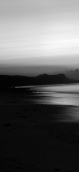 Serene black and white beach landscape with gentle waves under an overcast sky | 4K Wallpaper for Mobile