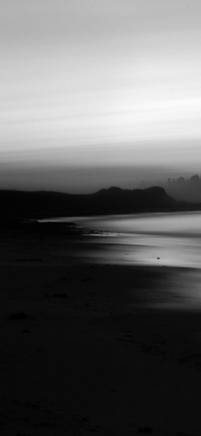 Serene black and white beach landscape with gentle waves under an overcast sky | 4K Wallpaper for Mobile