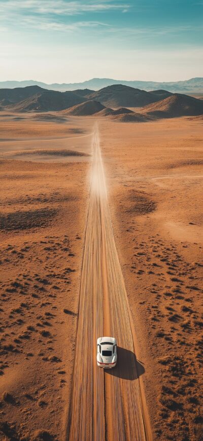 Desert landscape with a winding road, distant mountains, and a white car, exuding adventure and solitude | 4K Wallpaper for Mobile