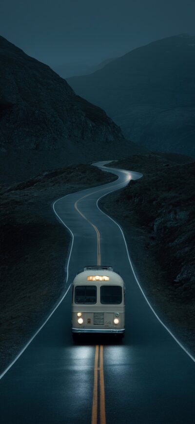 Vintage bus on a winding road in moody dark mountains under a serene sky | 4K Wallpaper for Mobile