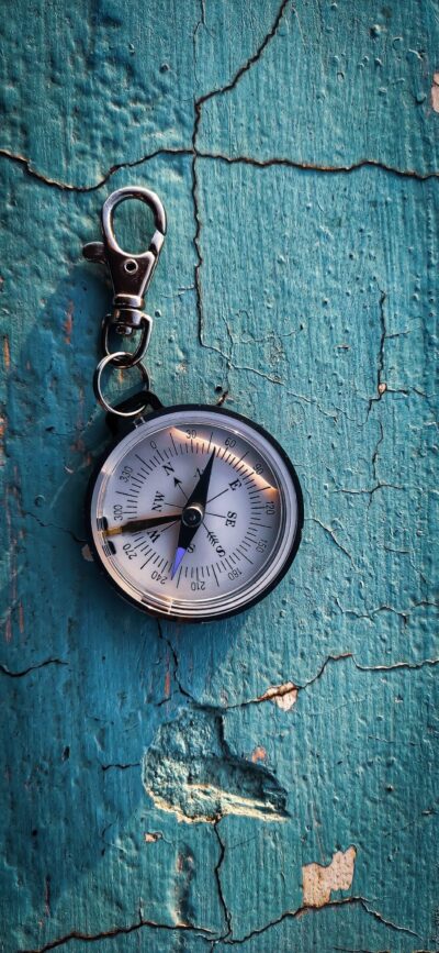 Vintage compass with metallic finish on weathered blue wood background, evoking adventure | 4K Wallpaper for Mobile