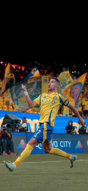 Soccer player in yellow and blue leaps with fans and banners in stadium background | 4K Wallpaper for Mobile | Yellow, Blue, Green