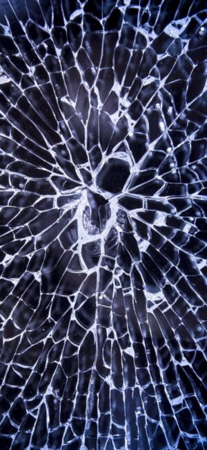 Close-up cracked glass with dark background, forming abstract web-like patterns. Colors include black, white, blue. | 4K Wallpaper for Mobile